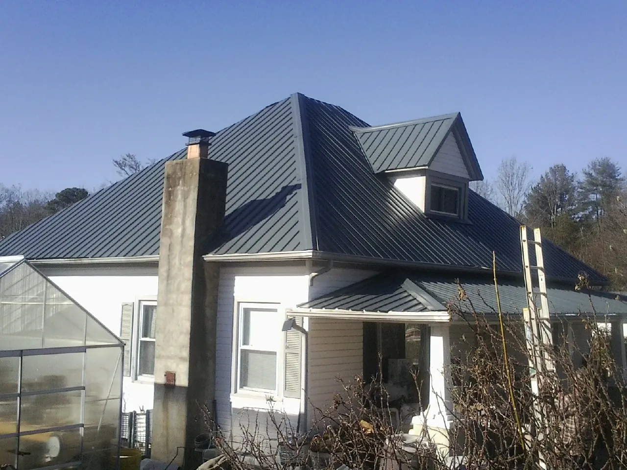 Dark blue standing seam metal roof on a white farmhouse with dormer — Slate & Tile Roof Repair by Roofing Brothers in Riegelsville