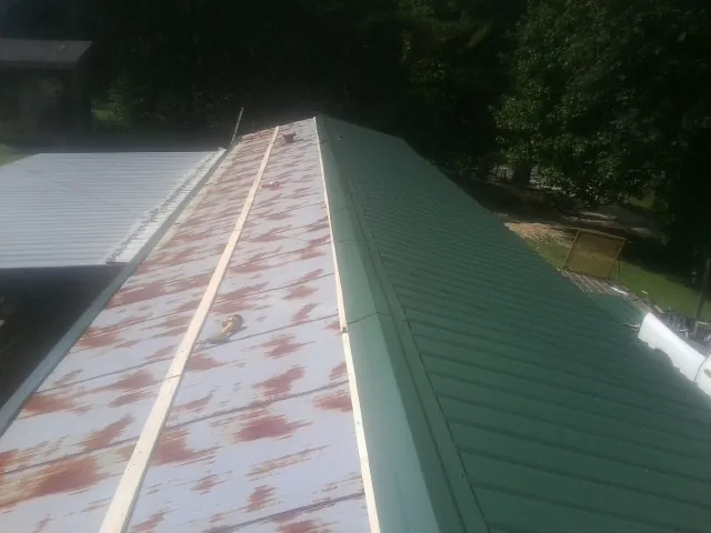 Old rusted panels beside newly installed green metal roofing — Wind Damage Roof Repair by Roofing Brothers in Riegelsville