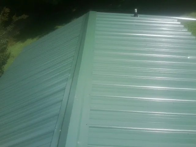 New green metal panels meeting at the ridge of a roof — Flat Roof Repair work by our crew in Riegelsville