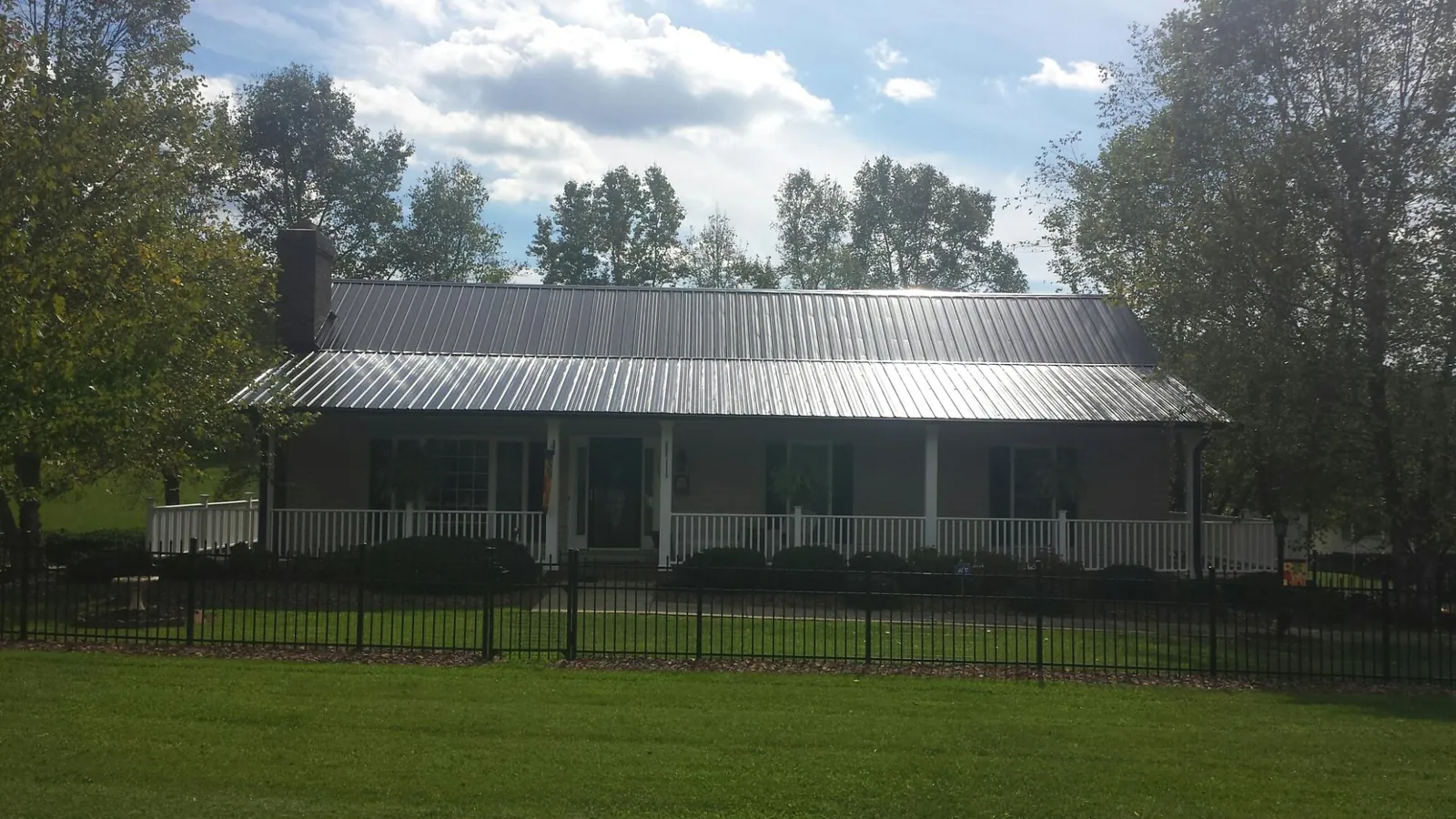 Gray metal roof on a brick ranch with a full width front porch — Gutter Guard Installation work by our crew in Riegelsville