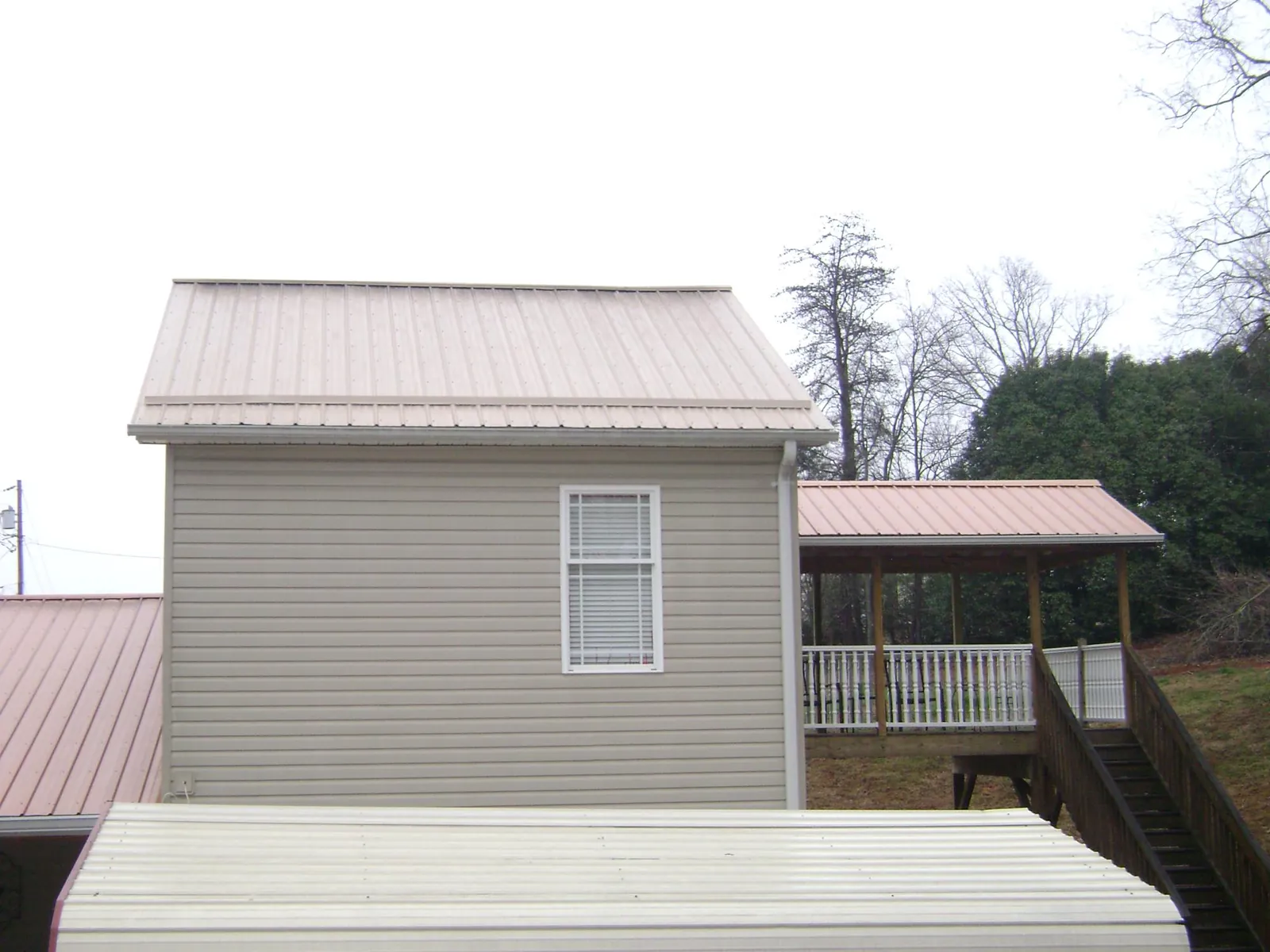Tan metal roofs on a two story addition and attached porch, from a Roof Replacement job in Riegelsville